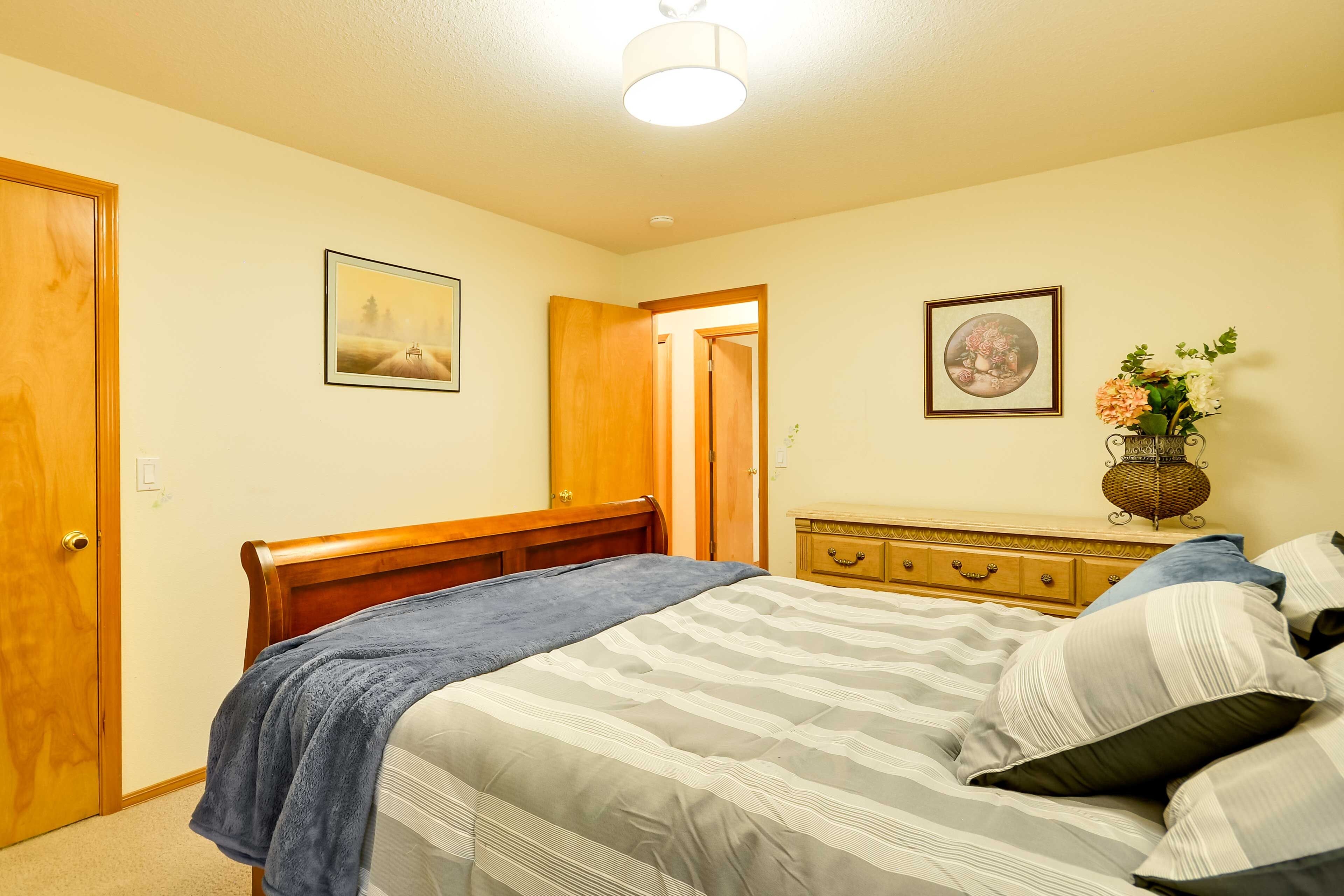 A bedroom with a bed, wooden headboard, a dresser, and a nightstand with a lamp.