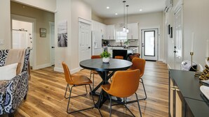 A modern kitchen with white cabinets, a central island, and a dining area with a round table and orange chairs. - Near CU & Dtwn! Campbellsville Home w/ Game Room (Campbellsville)