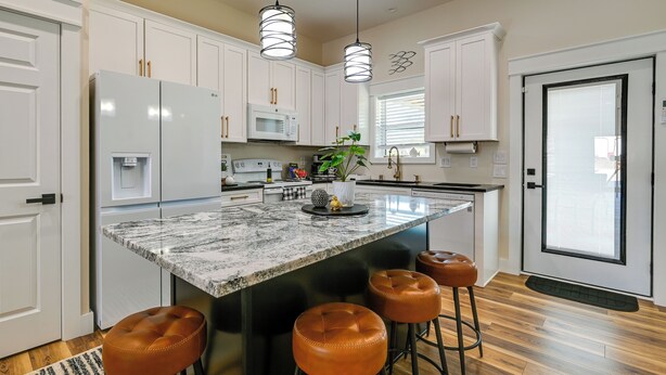 A modern kitchen with white cabinets, a granite island, and three bar stools. - Near CU & Dtwn! Campbellsville Home w/ Game Room (Campbellsville)
