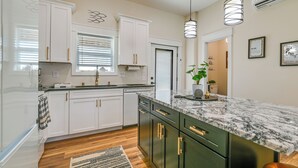 A modern kitchen with white and dark green cabinets, a marble countertop, and pendant lighting. - Near CU & Dtwn! Campbellsville Home w/ Game Room (Campbellsville)