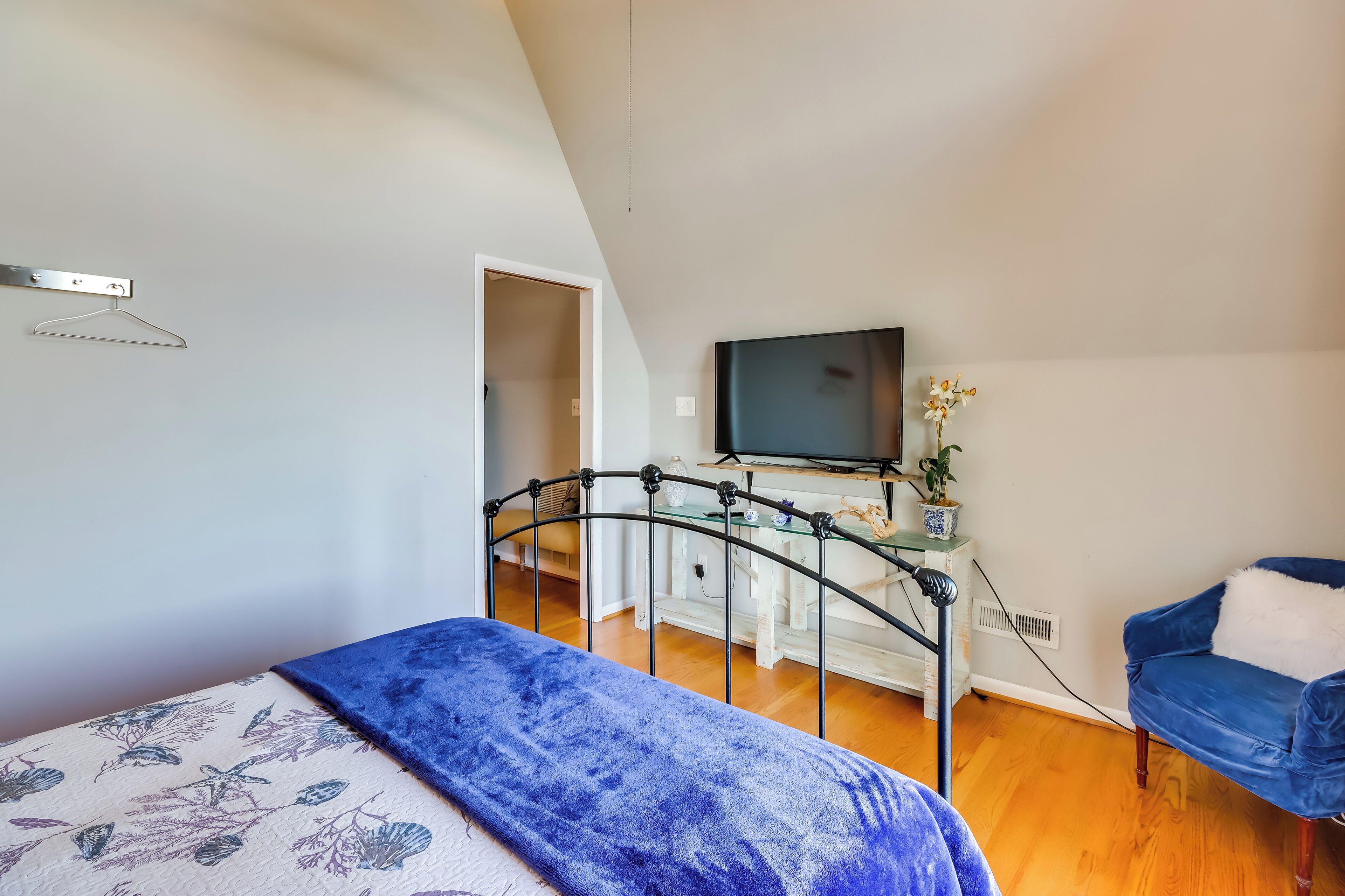 A bedroom with a bed, a desk, a chair, and a television.