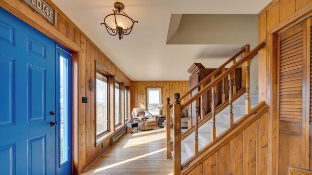A wooden interior with a blue door, a staircase, and a sofa in the background. - Charming Country Home in Laramie - 4 Mi to UW! (Laramie)
