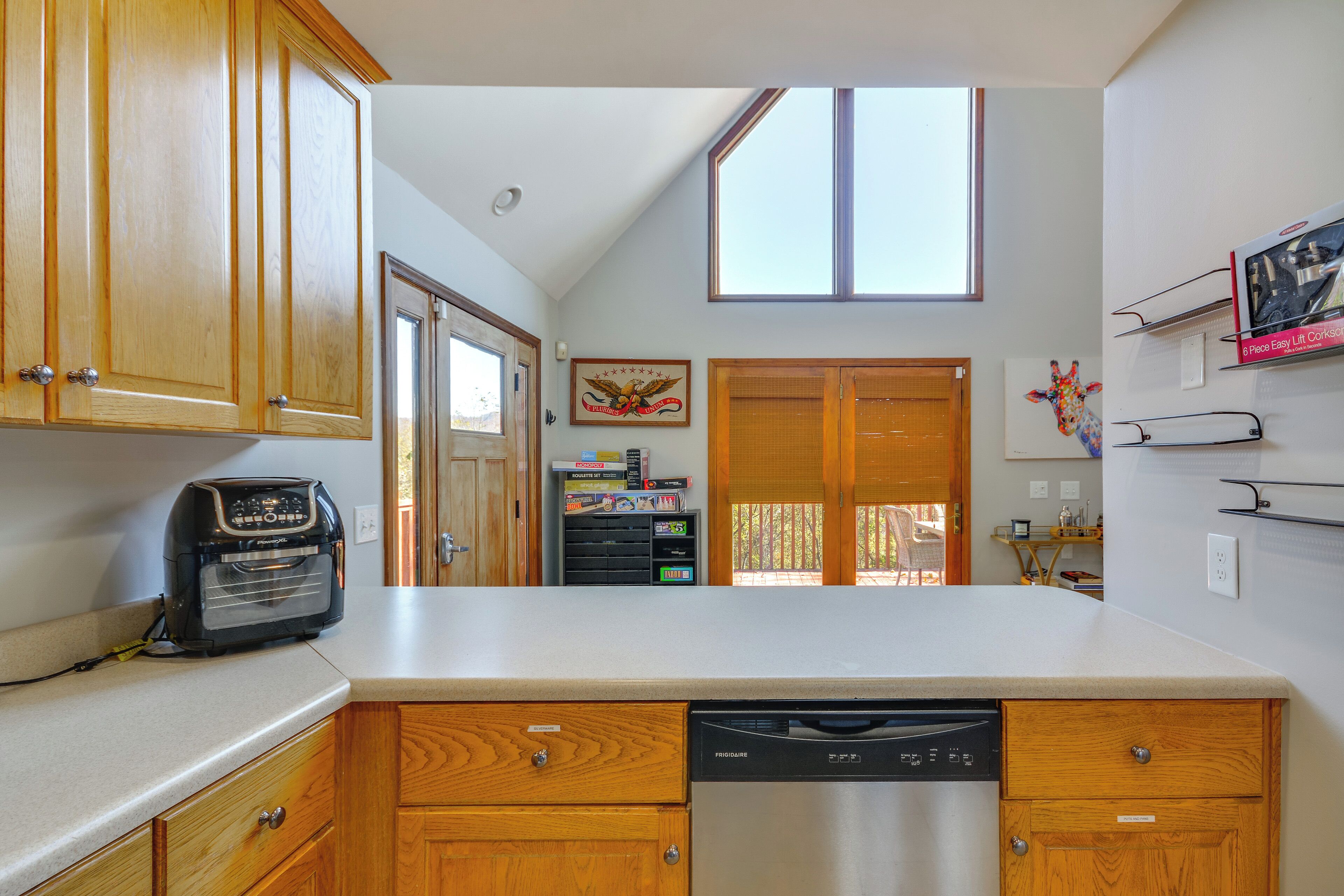 A kitchen with wooden cabinets, a dishwasher, and a window above the counter.