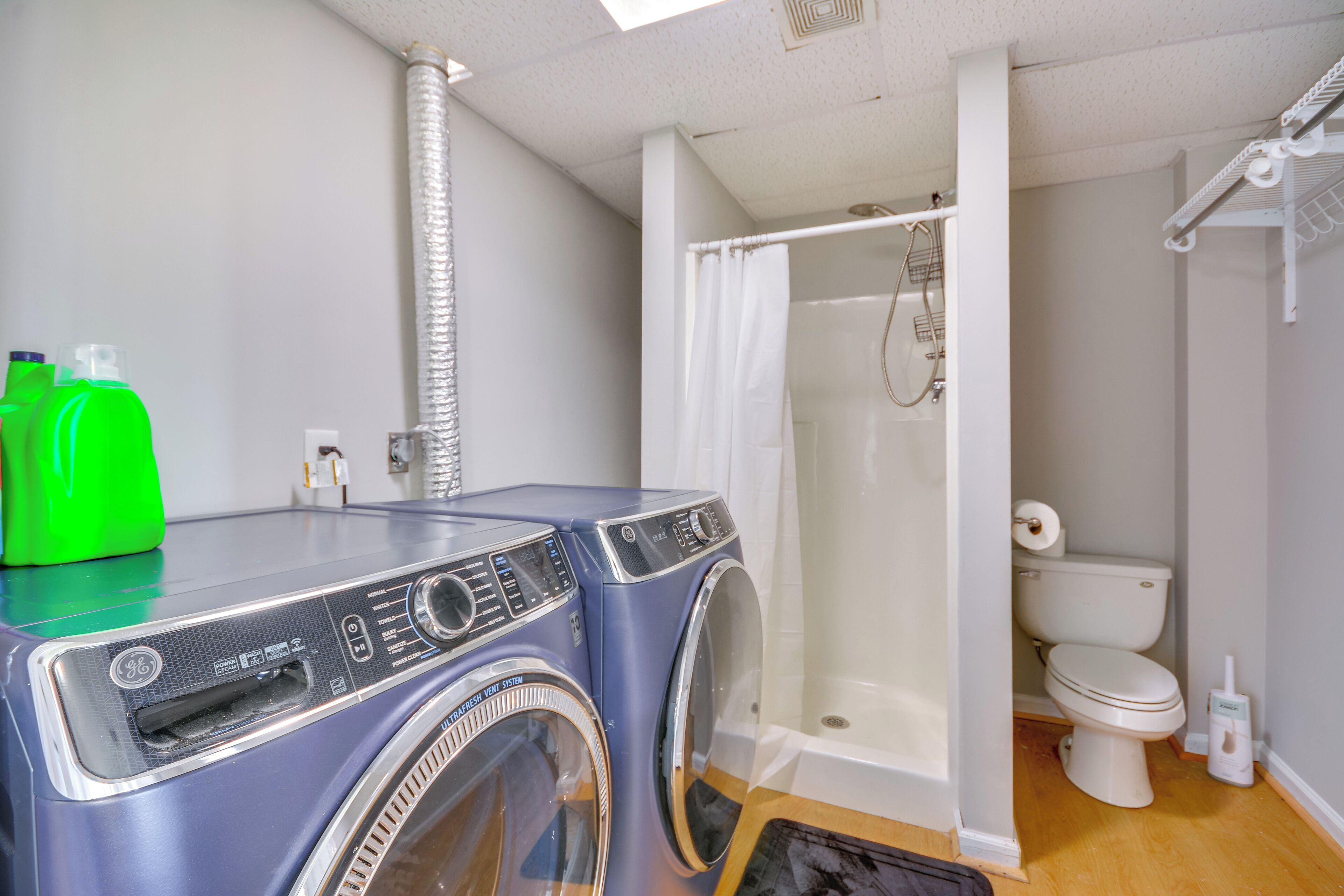 A compact bathroom with a built-in washer and dryer, a shower, and a toilet.
