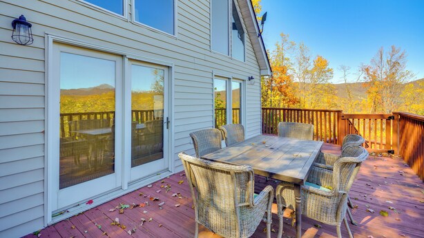 A covered patio with a table and chairs, large sliding glass doors, and a wooden deck. - Mountain-view Blue Ridge Cabin Getaway w/ Fire Pit (Callaway)