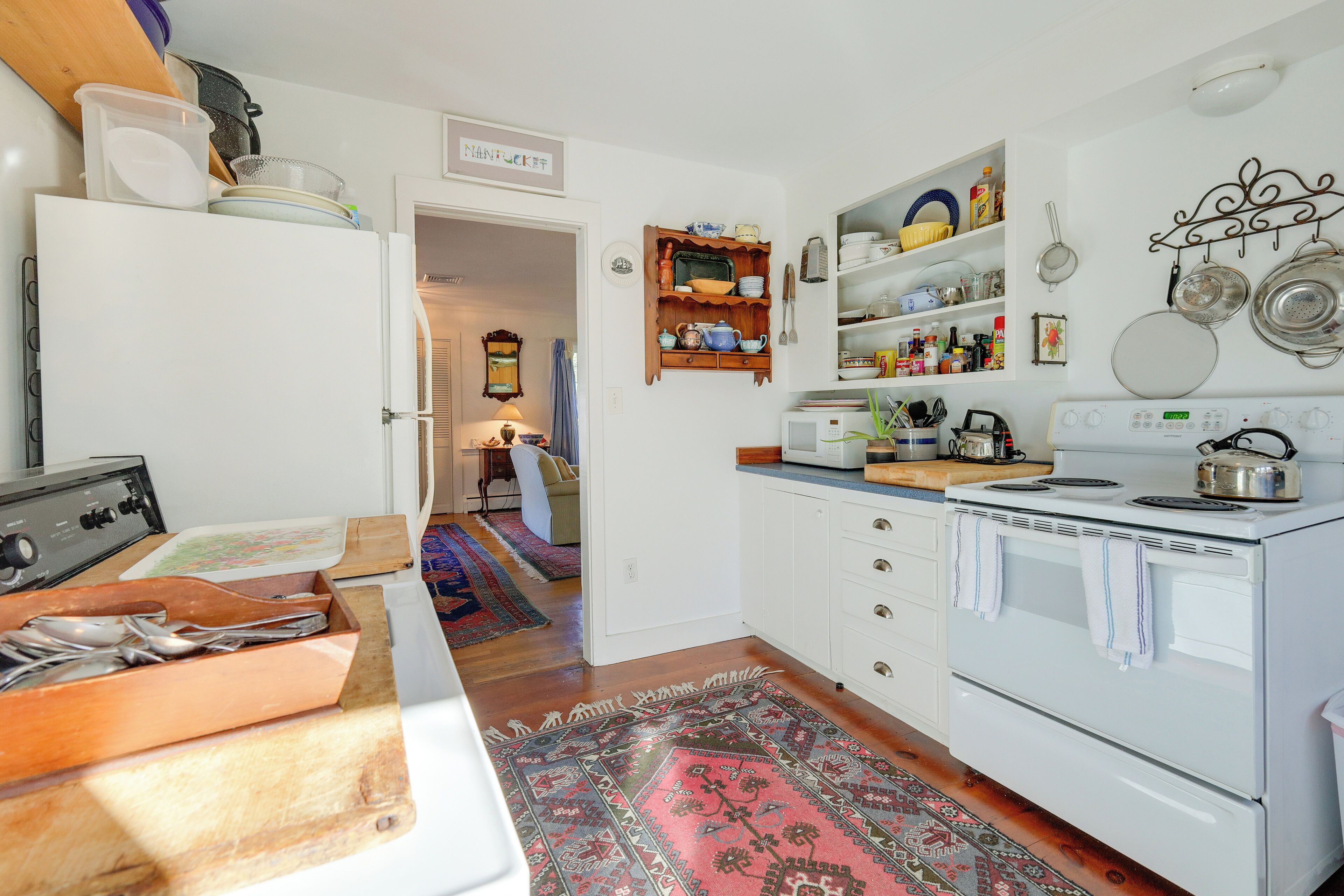 A kitchen with a stove, oven, and various kitchen utensils. There is a wooden cutting board and a sink.