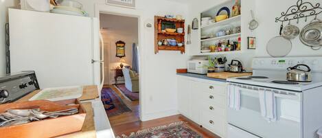 A kitchen with a stove, oven, and various kitchen utensils. There is a wooden cutting board and a sink.