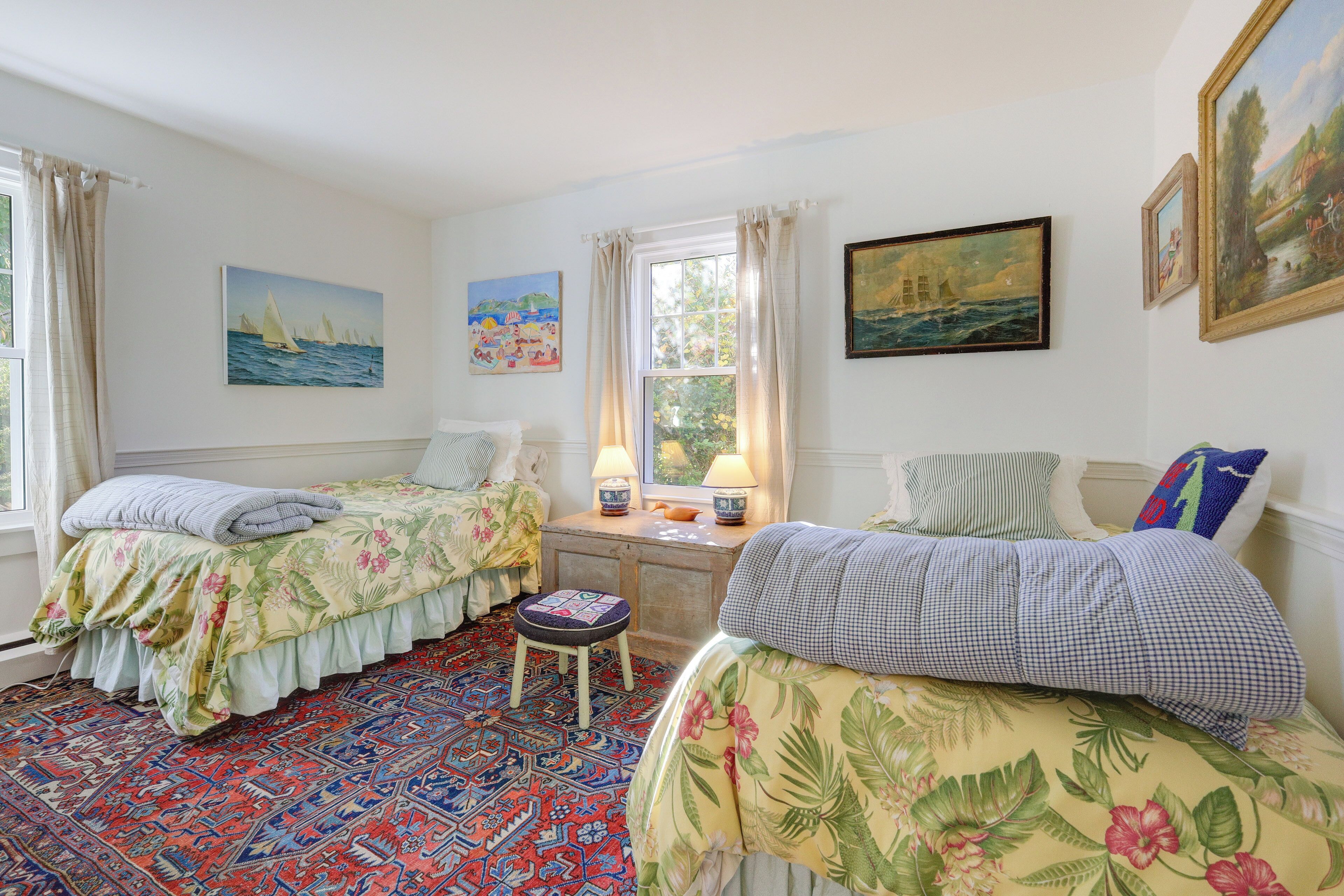 Een kamer met twee bedden, een raam met gordijnen en kunstwerken aan de wanden.