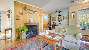 Ein gemütliches Wohnzimmer mit Kamin, Holzwänden, einem grünen Sofa und einem gemusterten Teppich.