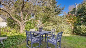 Eine Terrasse mit Tisch und Stühlen, umgeben von Grünpflanzen und Bäumen.