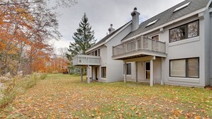 Une maison moderne à deux étages, dotée d’un patio couvert et d’une grande pelouse.