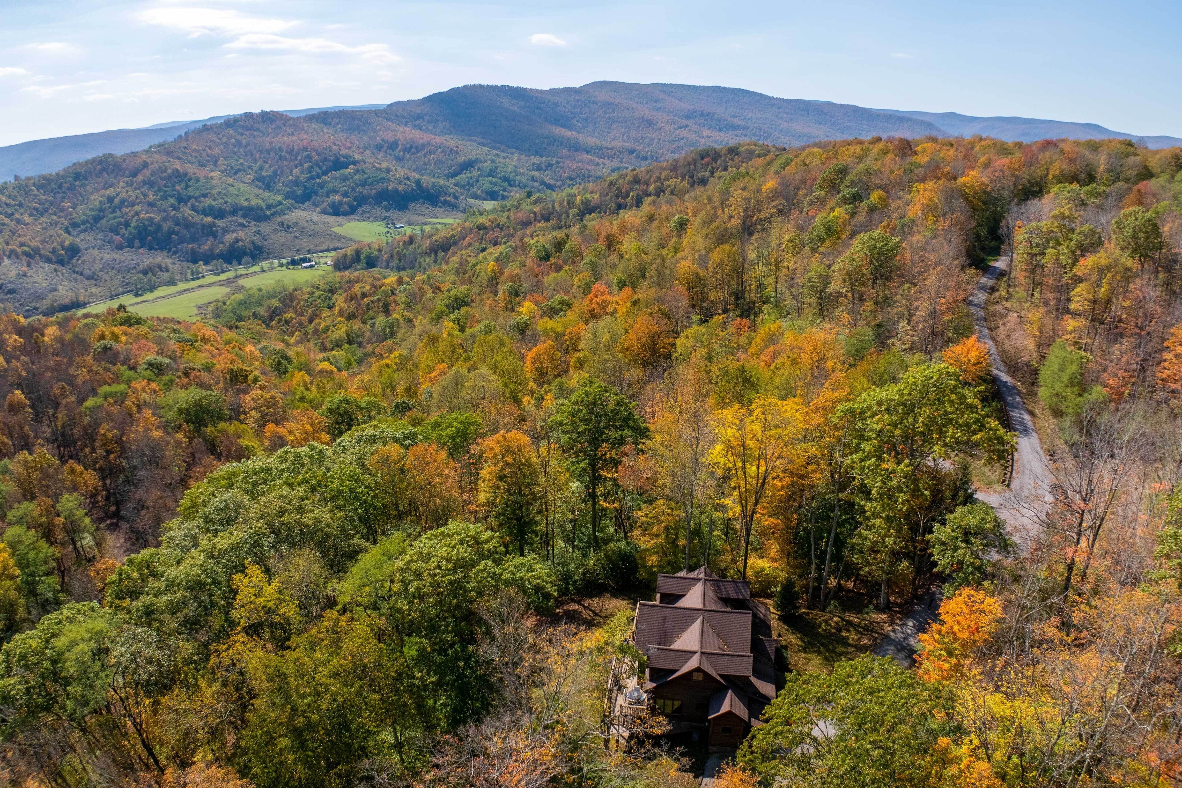 Une cabane nichée dans une vallée boisée, avec une chaîne de montagnes en toile de fond.