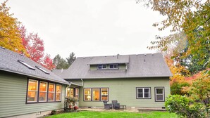 A two-story house with a green exterior, a covered patio with outdoor seating, and a well-maintained lawn. - Dog-friendly Milwaukie Home: 9 Mi to Dtwn Portland (Milwaukie)