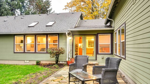 A house with a patio area featuring a table and two chairs, a small garden, and a visible door leading to an interior space. - Dog-friendly Milwaukie Home: 9 Mi to Dtwn Portland (Milwaukie)