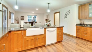 A modern kitchen with wooden cabinets, a large island, and pendant lighting. - Dog-friendly Milwaukie Home: 9 Mi to Dtwn Portland (Milwaukie)