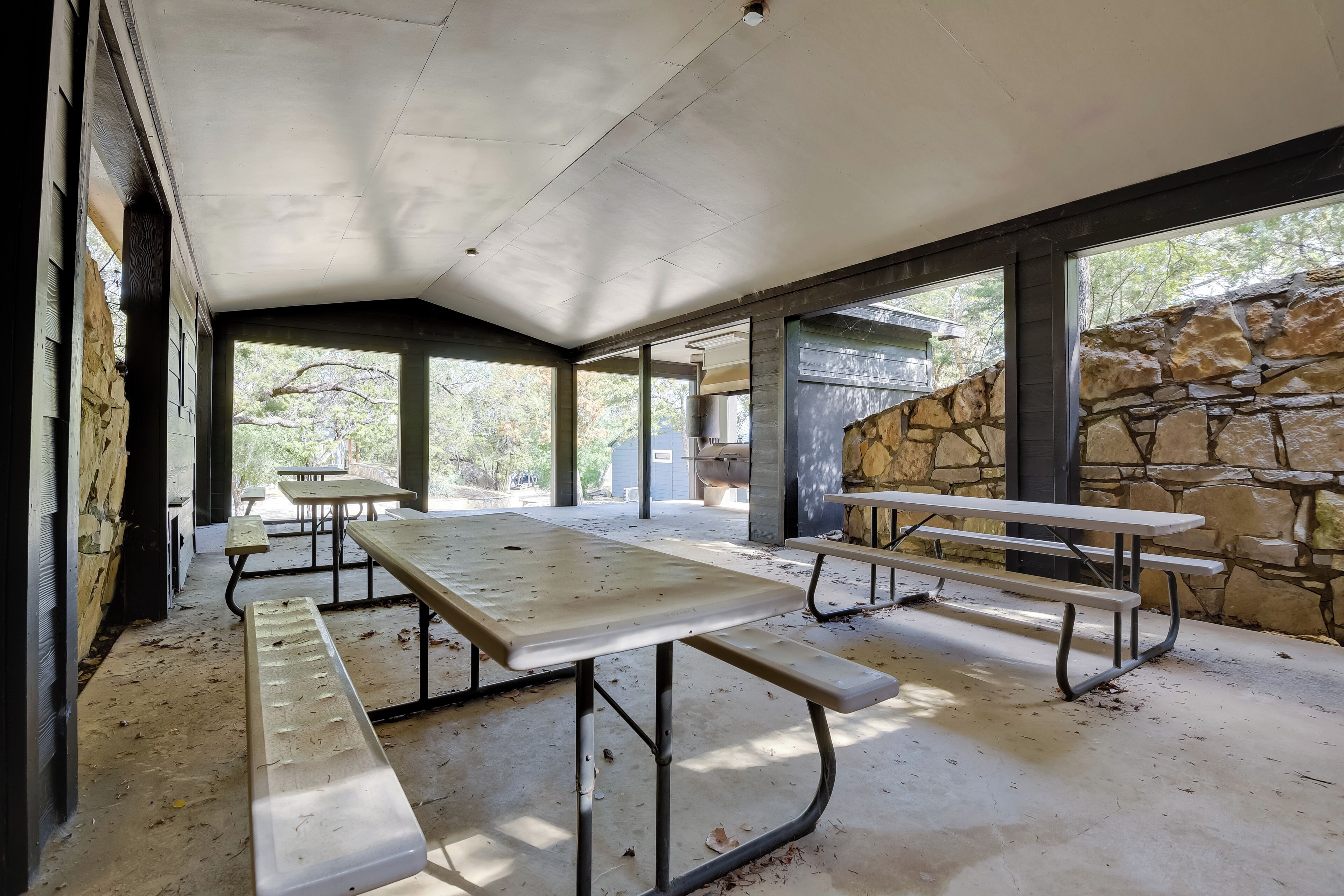 An outdoor covered picnic area with stone walls and benches.