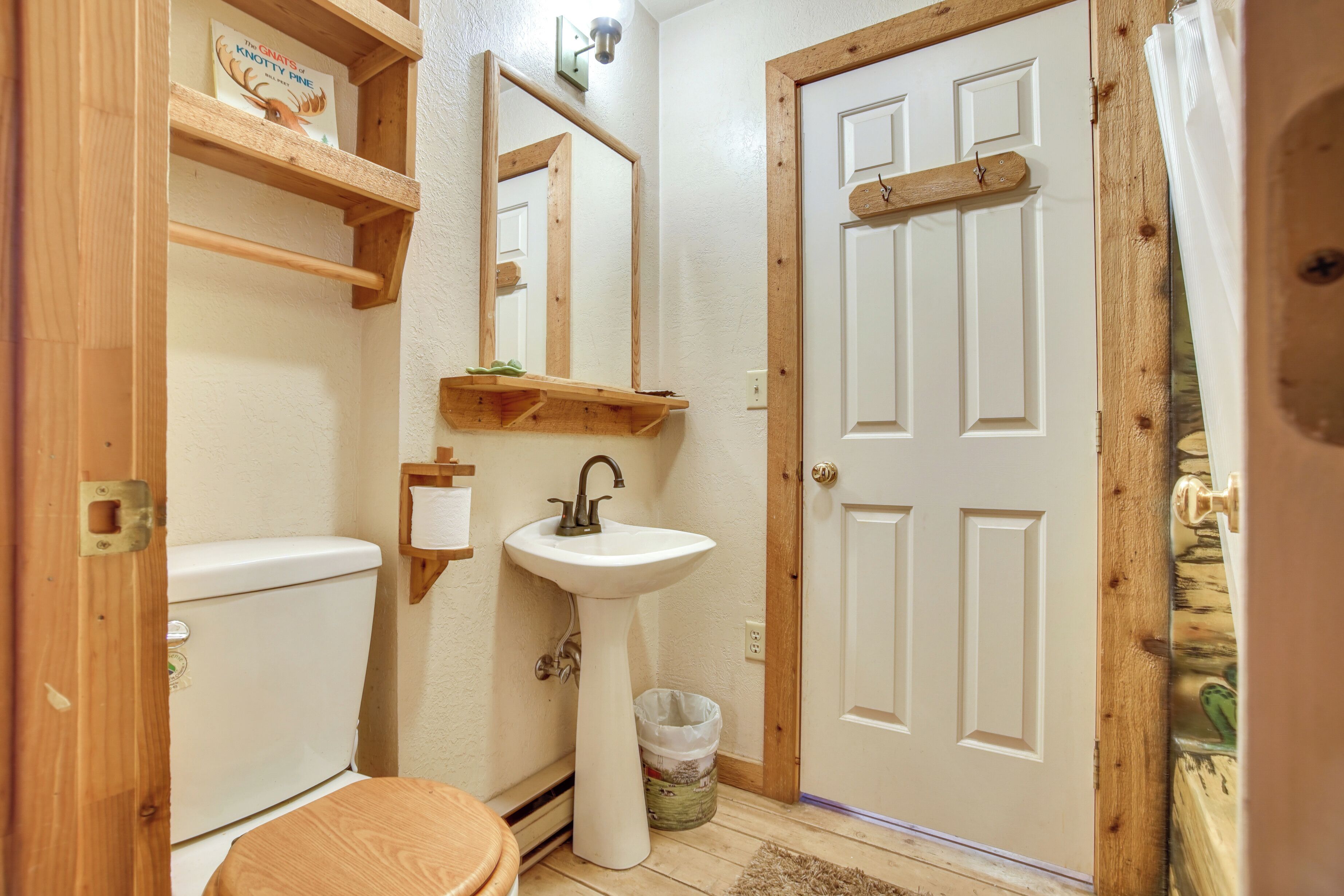 Un baño con puerta de madera, un lavabo blanco, un inodoro y un espejo.