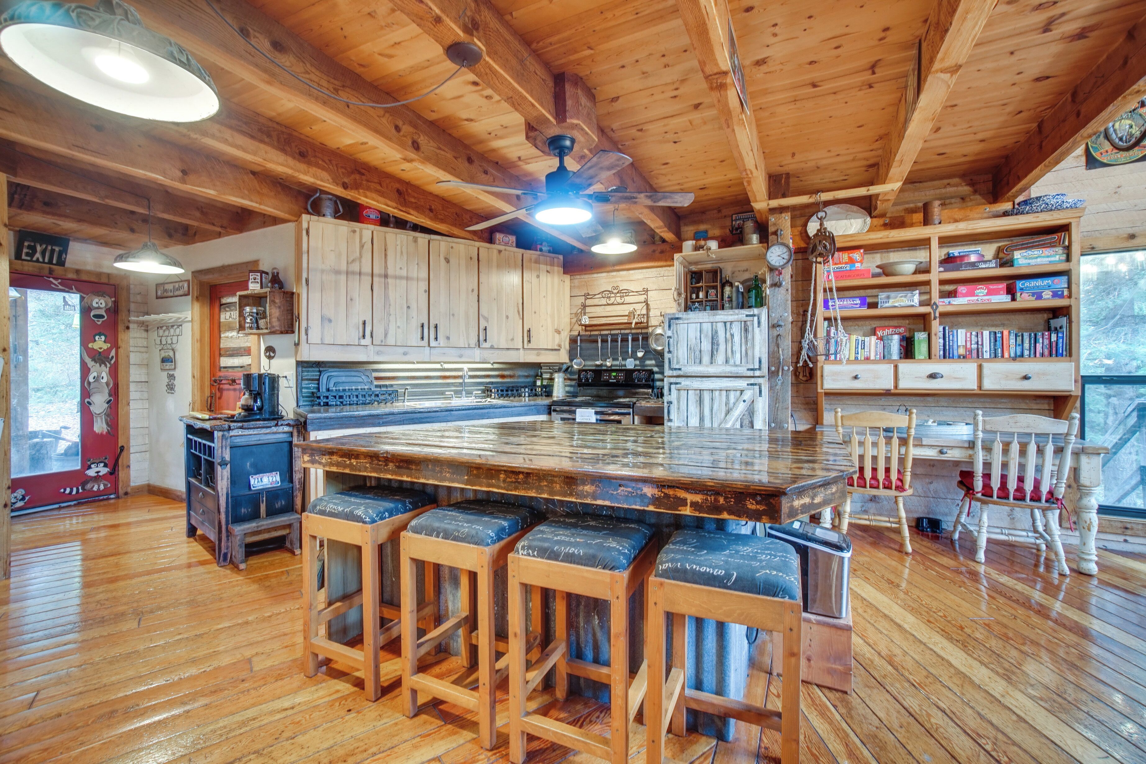 A rustic kitchen with wooden cabinets, a bar area with stools, and a large island.