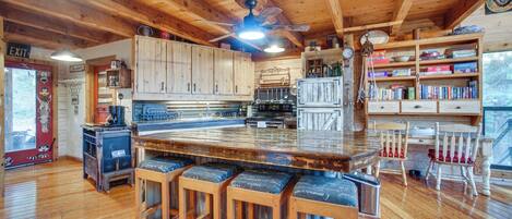 A rustic kitchen with wooden cabinets, a bar area with stools, and a large island.