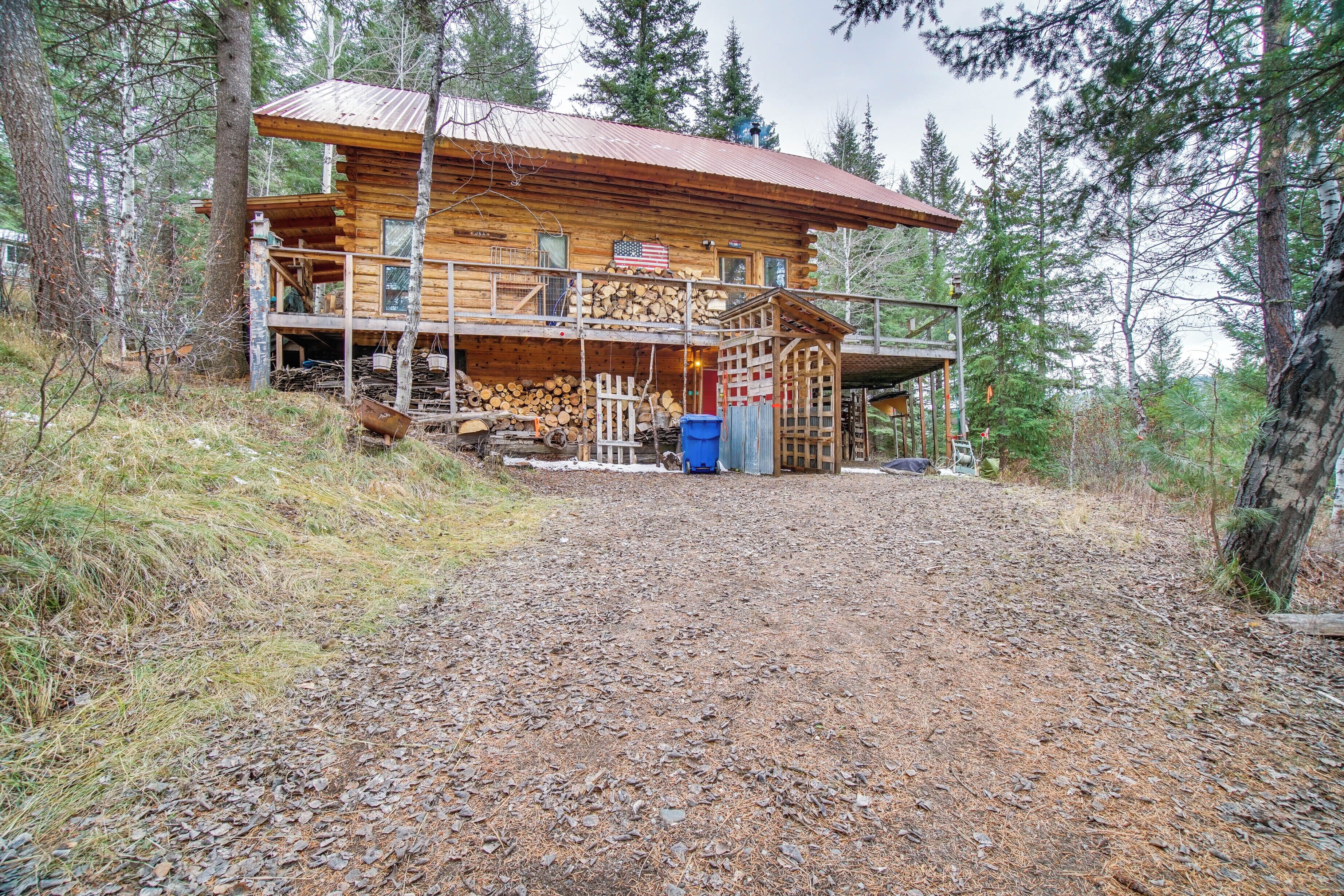 Eine Blockhütte mit Veranda, einer Treppe und einem Holzstapel davor.