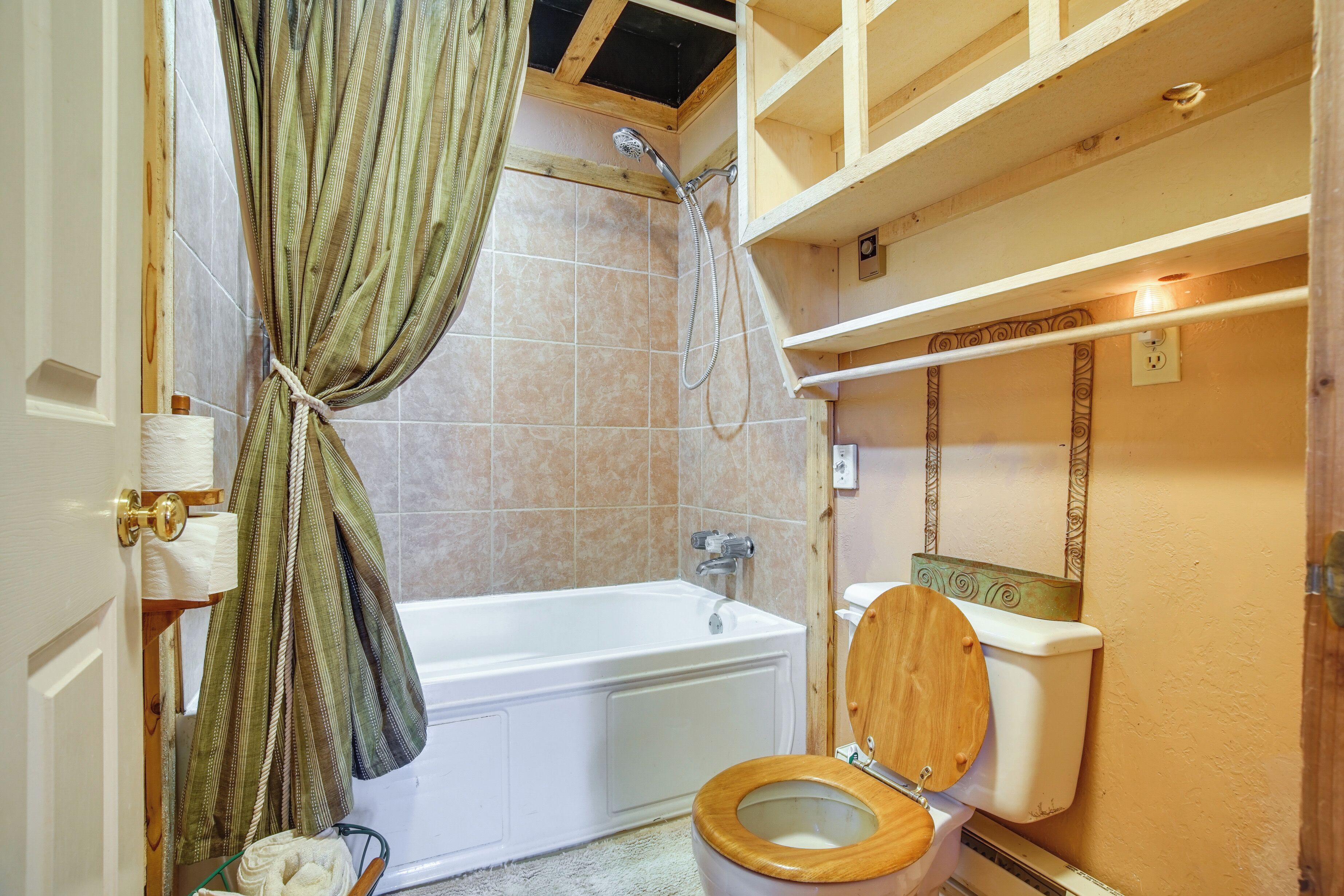 Un bagno con vasca, servizi igienici, doccia e mensole in legno.