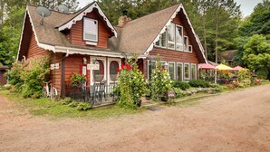 Een houten huis met een veranda, een bord waarop 'OPEN' staat en een fiets voor de deur.
