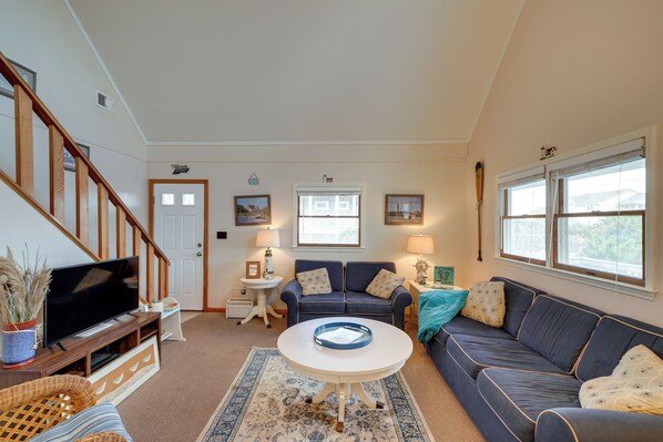A living room with a TV, sofas, a coffee table, and a staircase.