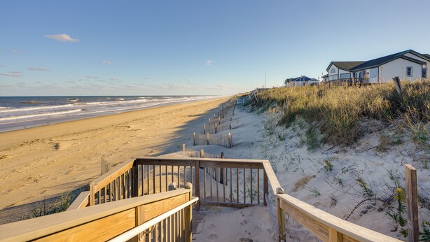 A beach with wooden walkways leading to a white building with a dark roof. - Kitty Hawk Vacation Rental w/ Private Pool! (Kitty Hawk)