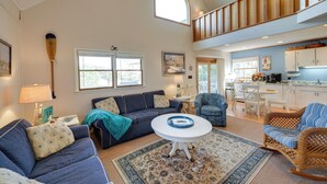 A spacious living area with a high ceiling, a dining table, and a kitchen in the background. - Kitty Hawk Vacation Rental w/ Private Pool! (Kitty Hawk)