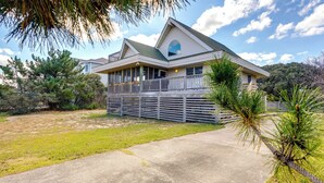 A two-story house with a balcony, a garage, and a driveway. - Kitty Hawk Vacation Rental w/ Private Pool! (Kitty Hawk)