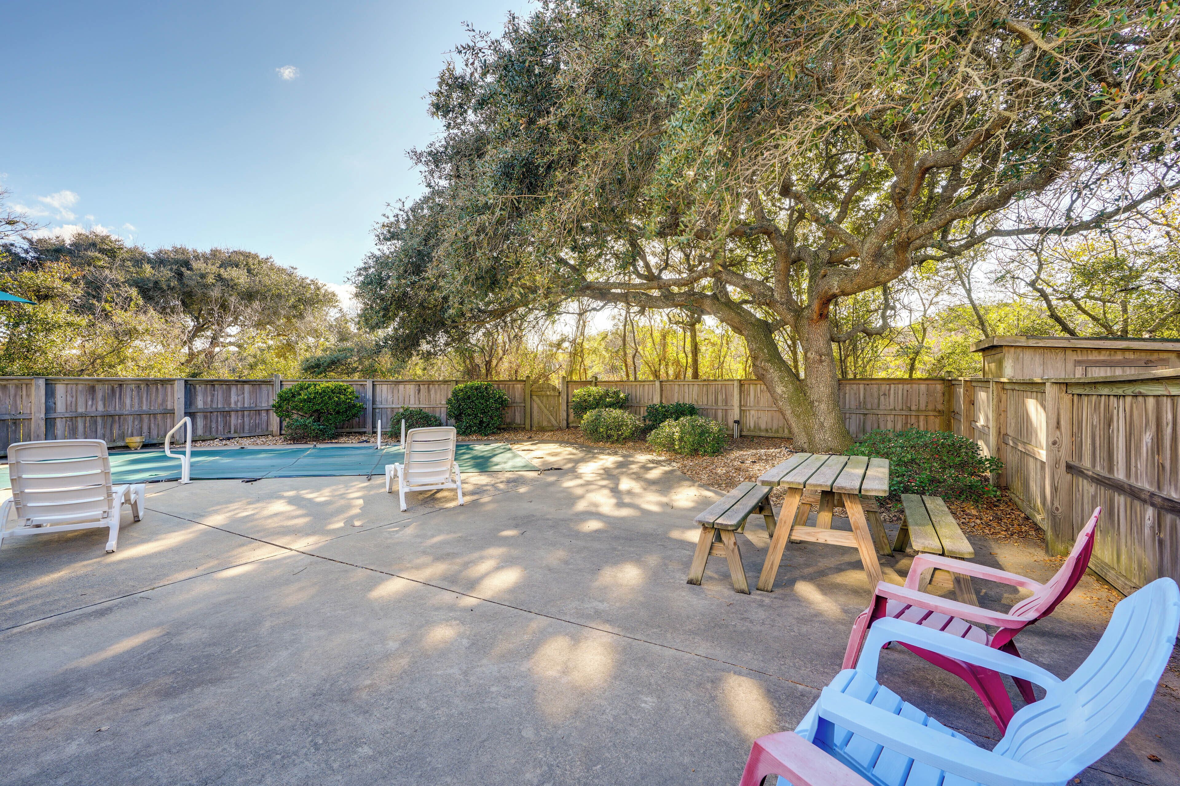 A backyard with a swimming pool, patio furniture, and a wooden fence.