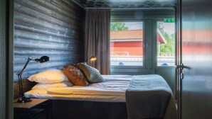 A room with a bed, a desk, a lamp, and a window with a view of a building outside. - Norrf ällsvikens Rum & Kök (Mjällom)