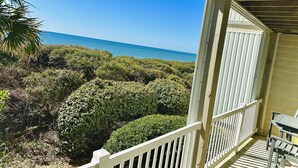 A wooden balcony with a view of the ocean and dense vegetation. - Oceanfront, Ocean Club F101, Linens included, 3Br 2ba, pool (Salter Path)