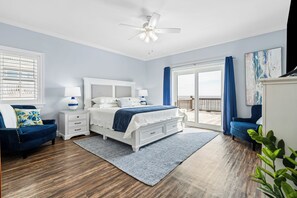 Relax in this serene bedroom with a large bed, bedside tables, and a ceiling fan, leading to an outdoor area through a sliding glass door.