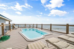 Relax by the pool surrounded by lounge chairs and a calm view.