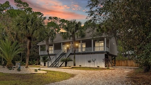 A two-story house with a covered porch, a staircase, and a gravel driveway. - Stay like a local in this pet-friendly home with private pool!  (Dauphin Island)