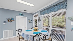 A dining area with a round table, chairs, and decorative wall art. - Stay like a local in this pet-friendly home with private pool!  (Dauphin Island)