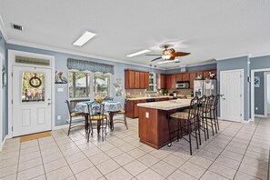 Una cocina amplia con una isla central, armarios de madera y una zona de comedor con mesa y sillas.