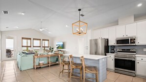 A modern kitchen with white cabinets, stainless steel appliances, and a central island with chairs.