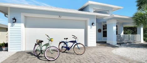 A two-story house with a garage, two bicycles parked in front, and a well-maintained driveway.