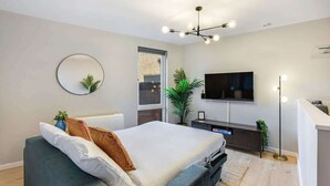 A modern bedroom with a bed, a TV, a round mirror, and a plant. - Host & Stay | Ropewalks Quarters III (Liverpool)