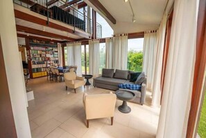 Relax in this spacious living area with a mezzanine level, featuring a sofa set, coffee table, and bookshelf.