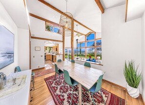 Un comedor espacioso con una gran mesa de madera, varias sillas y vistas al exterior a través de amplios ventanales.