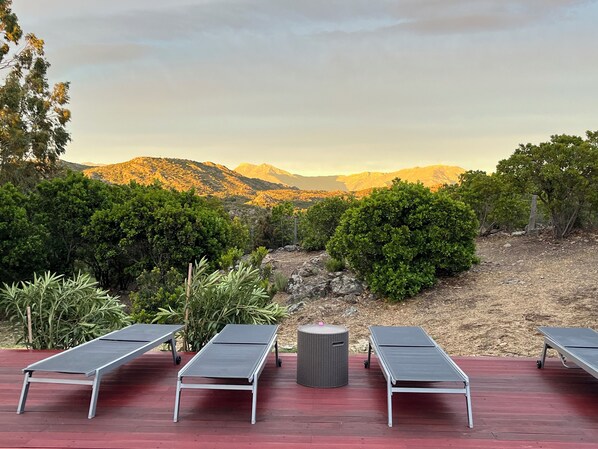 Une terrasse dotée de quatre chaises longues donnant sur un paysage montagneux.