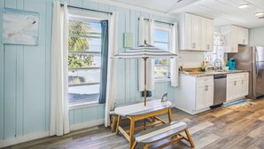A kitchen with wooden cabinets, a stainless steel refrigerator, and a dining area with a table and bench.