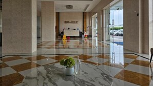 A hotel lobby with a checkered floor, a reception desk, and a large window. - Sky House BSD by Kakarama Room (Pagedangan)