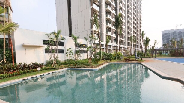 A swimming pool surrounded by greenery and tall buildings. - Sky House BSD by Kakarama Room (Pagedangan)