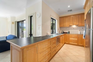 Una cucina moderna con pensili in legno, un piano di lavoro nero e un frigorifero in acciaio inossidabile.