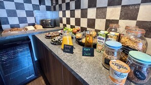 A breakfast buffet with various food items and beverages. - The Stag (Alcester)