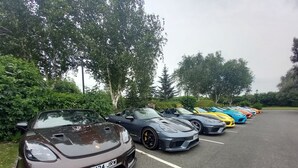 A row of luxury sports cars parked in a lot with trees in the background. - The Stag (Alcester)